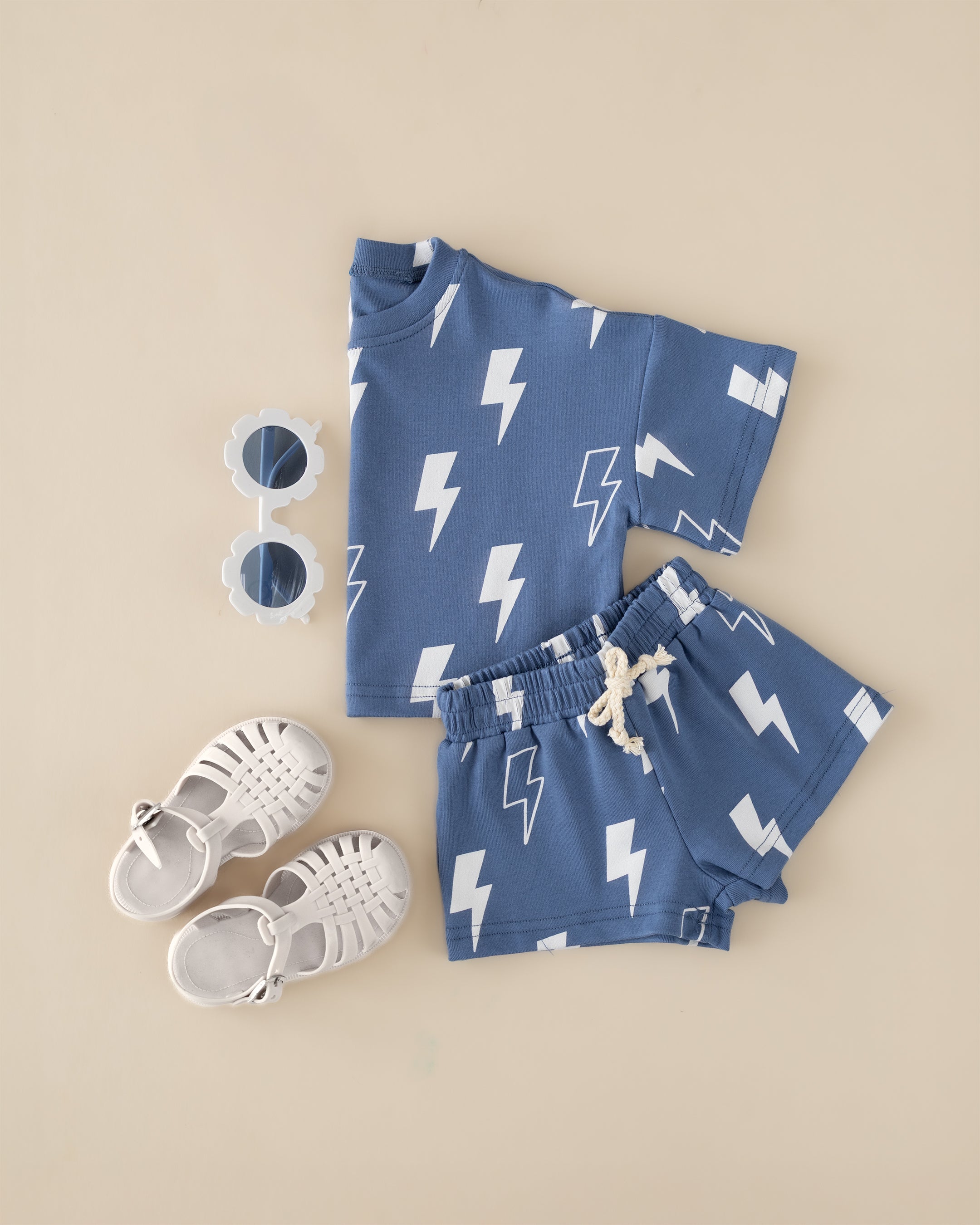 Blue bolts shorts set with oversized tee, matching shorts, and white sandals, perfect for kids' summer adventures.