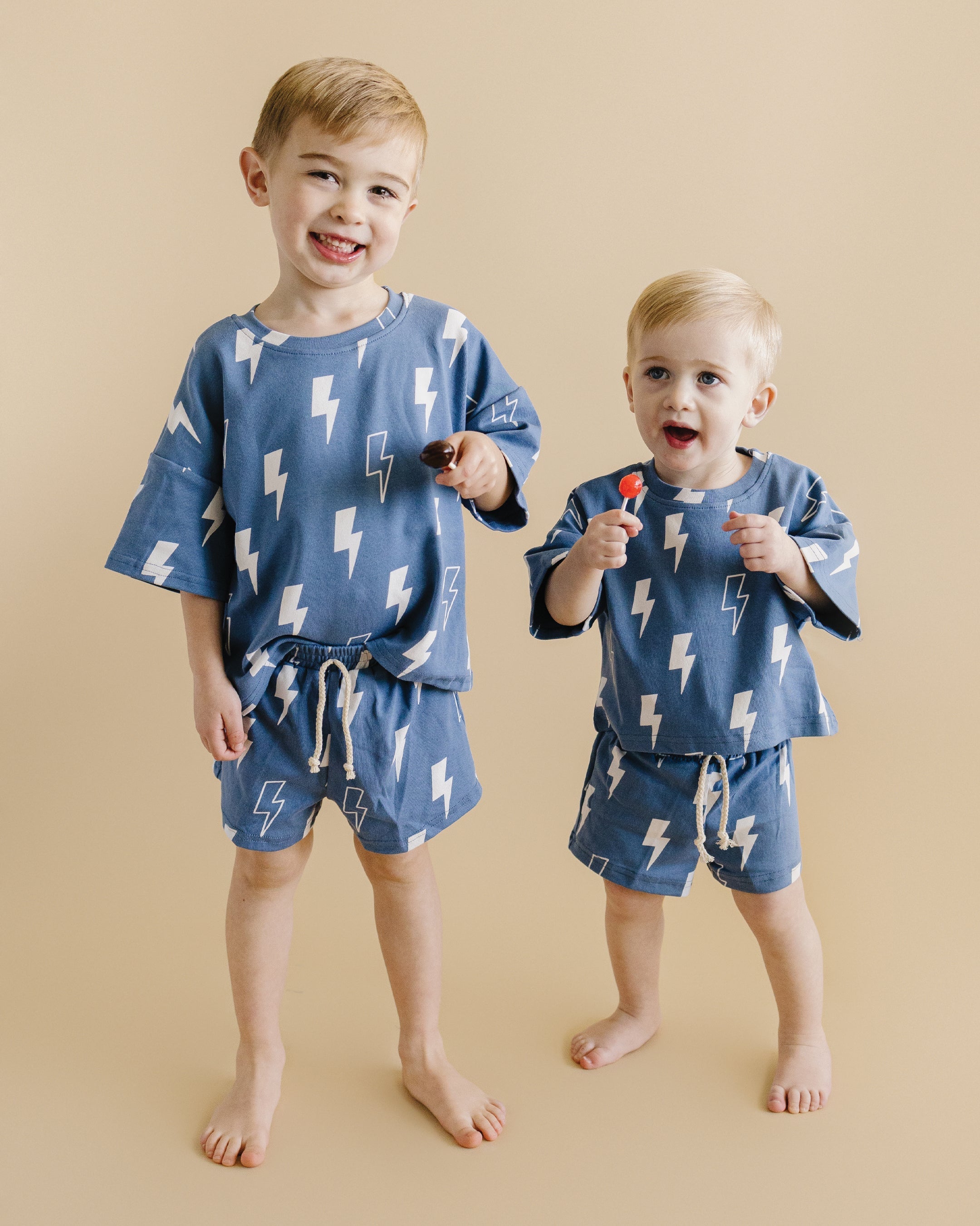 Two playful kids wearing Blue Bolts shorts set, featuring oversized tee and matching shorts with lightning prints.
