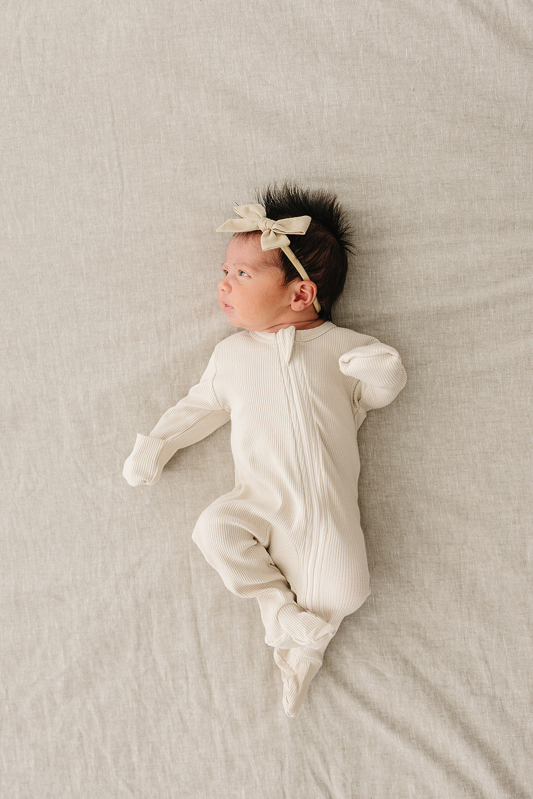 Vanilla organic cotton baby zipper sleeper on a soft surface, showcasing its comfort and style.