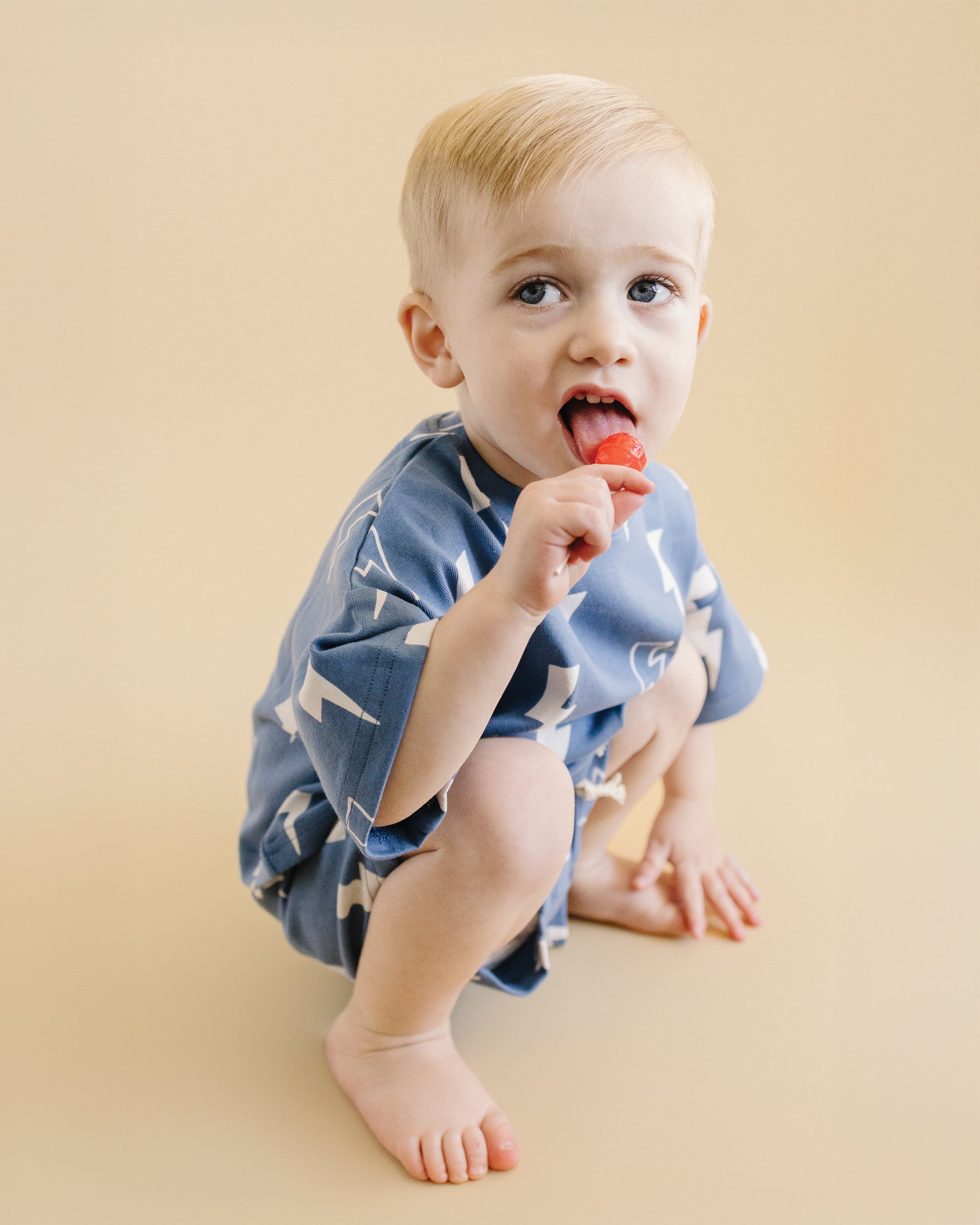Child enjoying a snack in a playful blue bolt shorts set, showcasing a relaxed-fit tee and matching shorts.