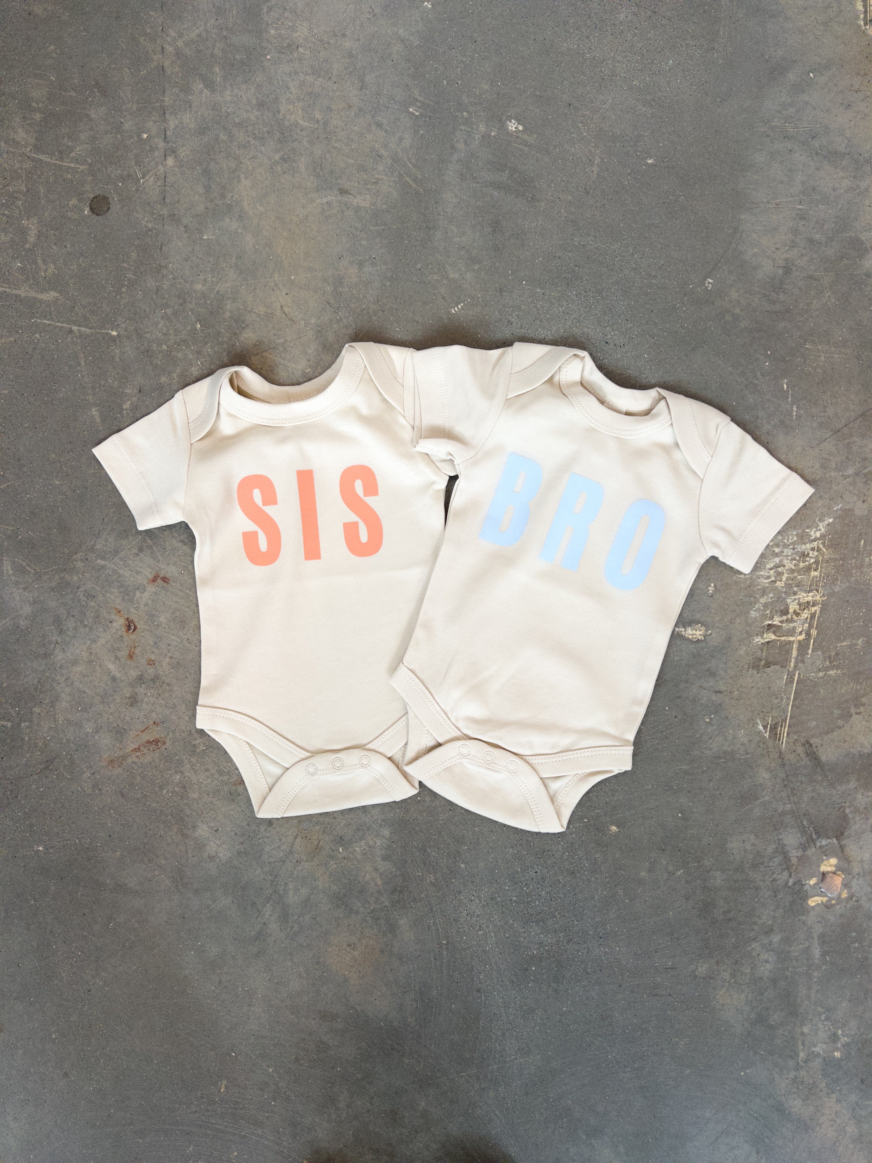 SIS + BRO organic baby onesies in neutral colors, perfect for sibling outfits and baby shower gifts.