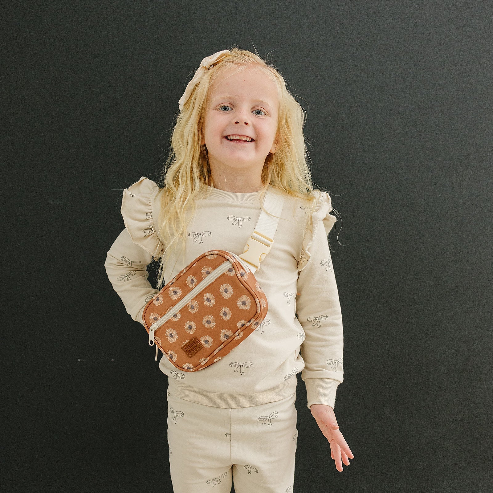Smiling girl wearing a Terracotta Sunflower Mini Fanny Pack, showcasing a cheerful sunflower print.