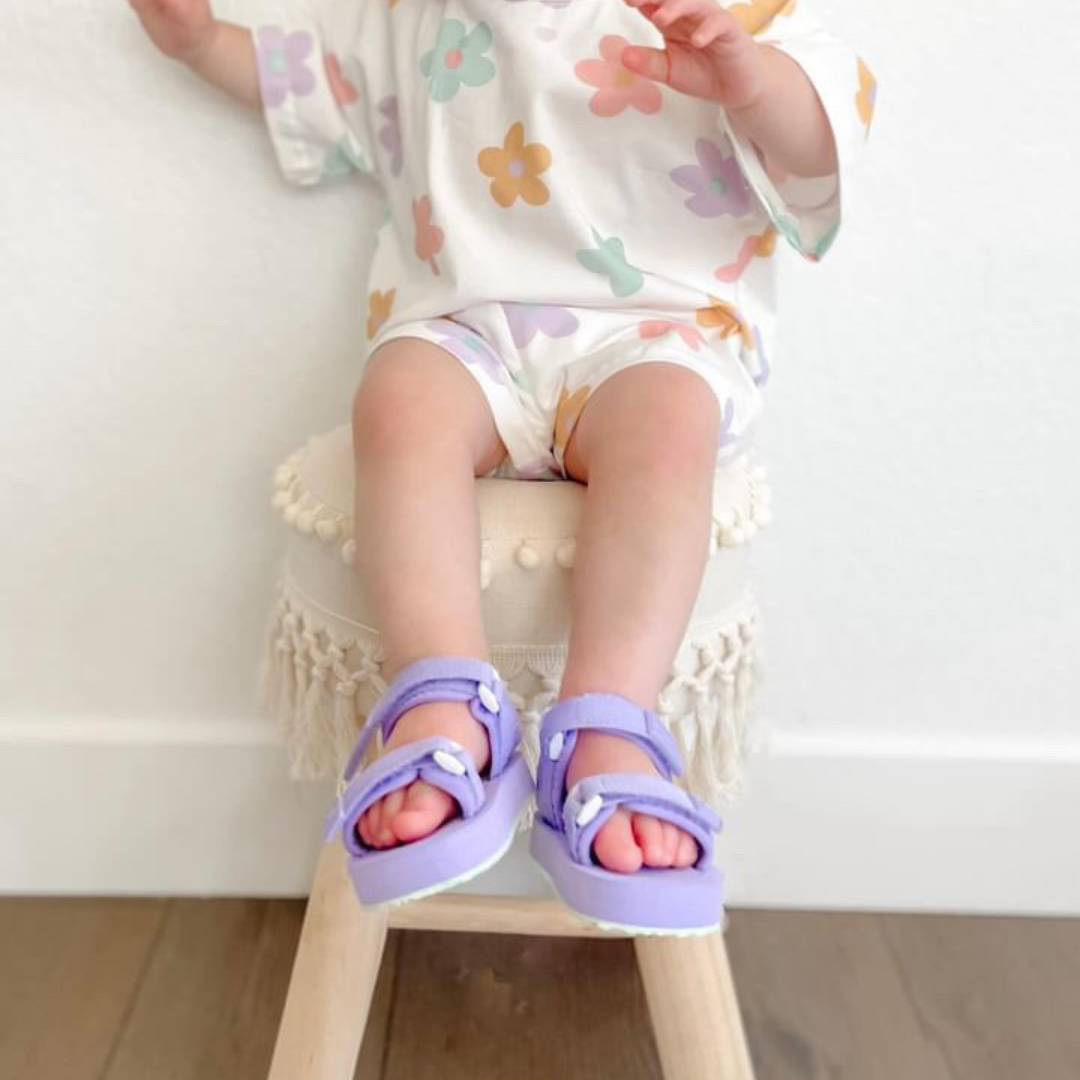 Toddler in colorful outfit wearing lightweight lavender Ned Sandal Water Shoes, perfect for summer adventures.