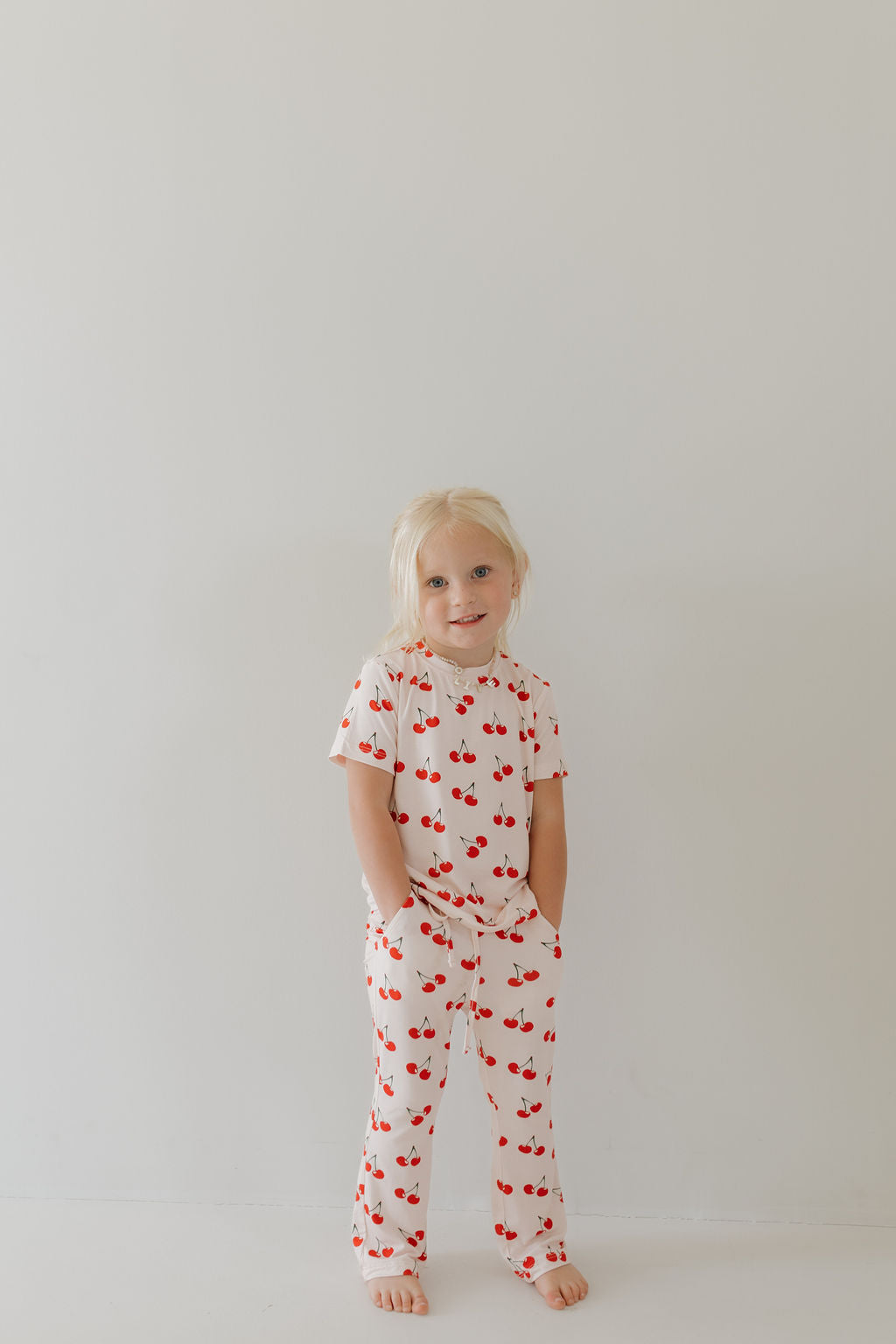 Toddler in short sleeve cherry print bamboo lounge set, smiling, showing playful and cozy style.