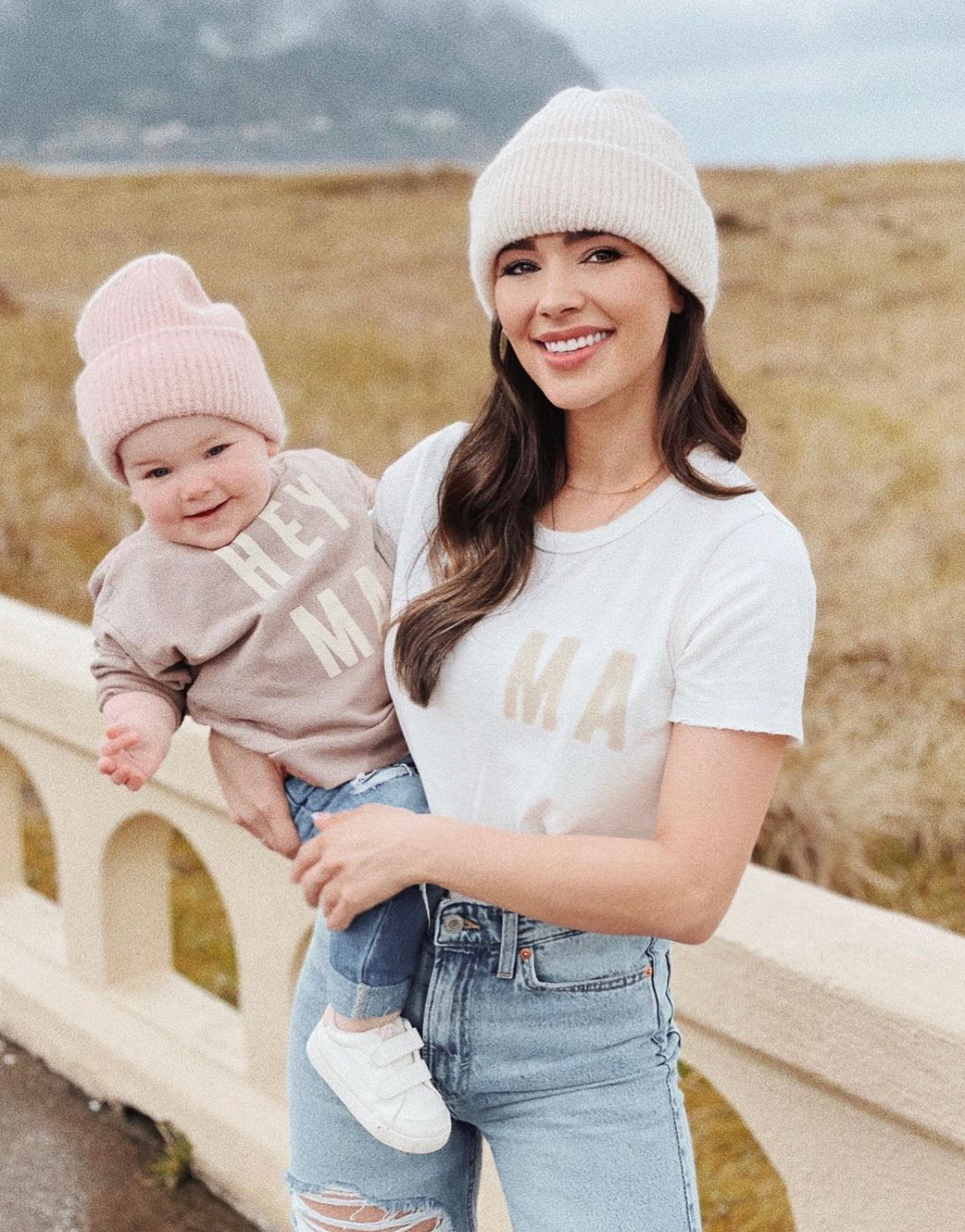 Mom and baby wearing matching Organic Vintage MA Tees, showcasing a cozy outdoor scene with soft knit hats.