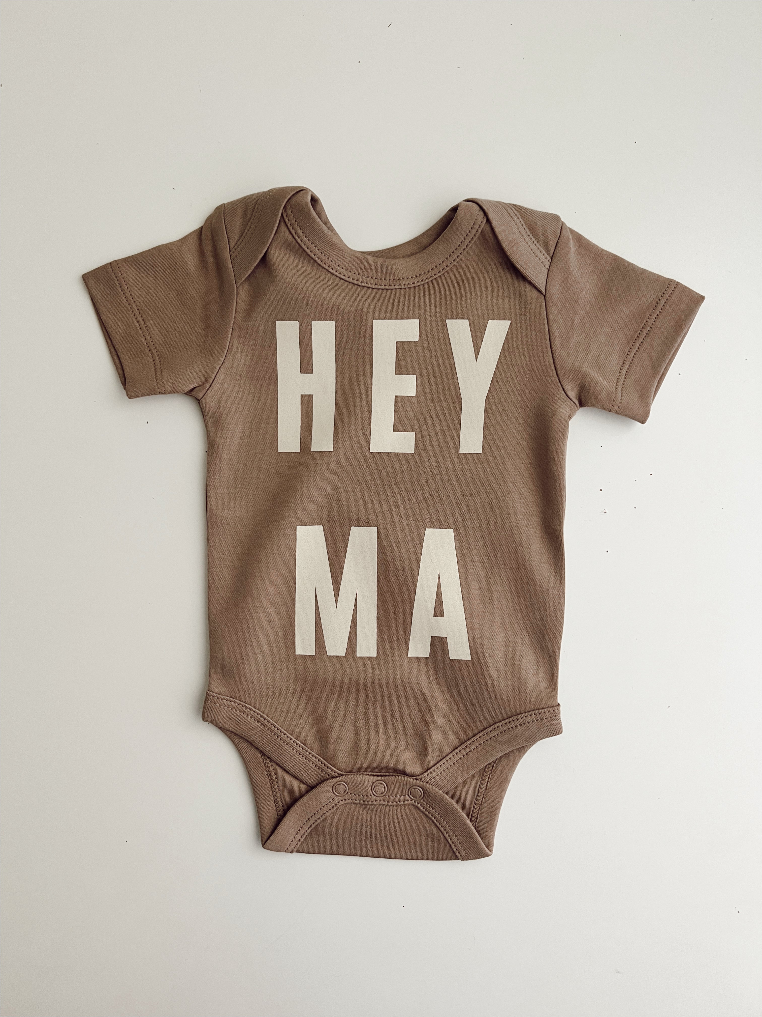 Cream organic baby onesie with 'HEY MA' design for trendy, ethically made baby clothes.